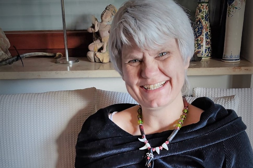 Portrait von Ute Friesen, sitzend, mit einem Kordkleid bekleidet und mit einer chinesischen Kette um den Hals